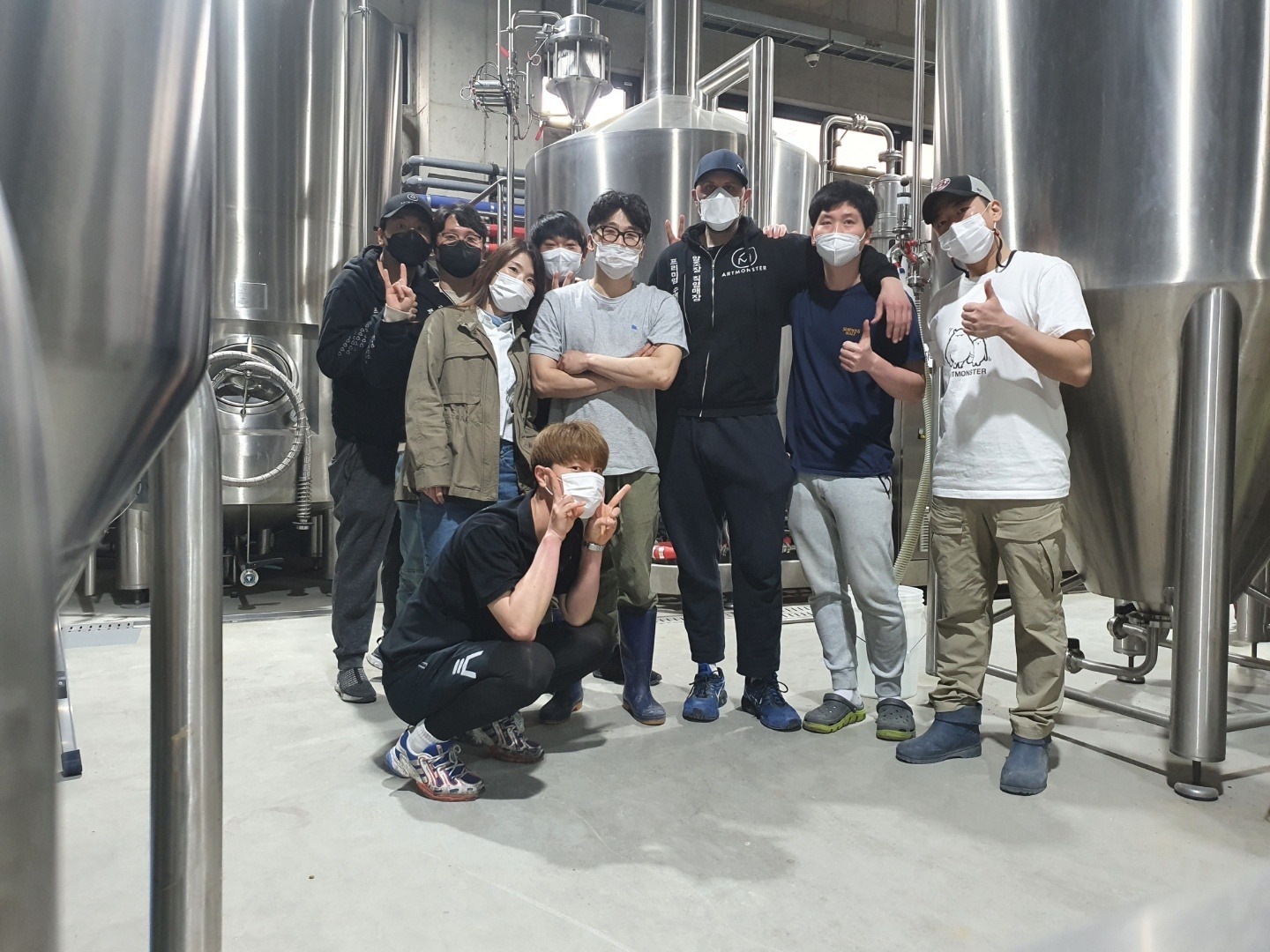Artmonster brewery team standing between stainless steel tanks