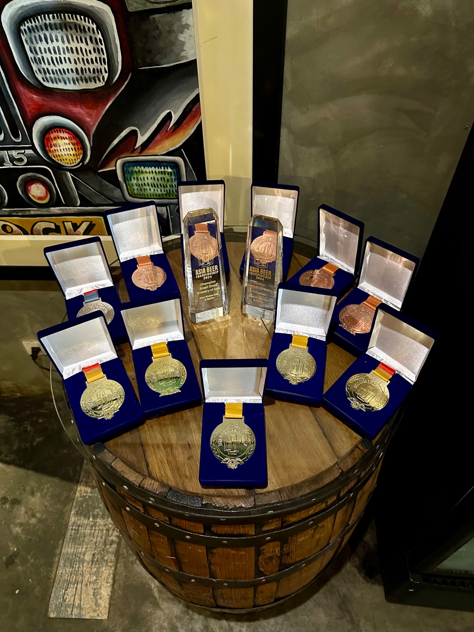 Asia Beer Championship medals and trophies displayed on a barrel